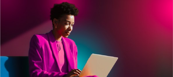 A broker working on a laptop, lit in JetPay pink and blue
